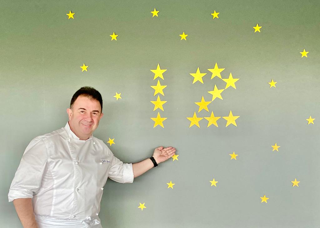 Martin Berasategui fotografiat langa un perete cu 12 stele galbene reprezentand stelele michelin
