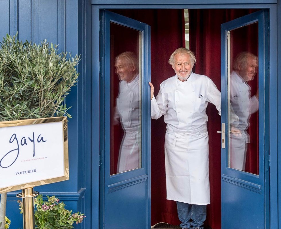 Pierre Gagnaire in uniforma de bucatar, fotografiat in usa restaurantului, cu usi albastre, unul din cei mai buni bucătari din lume