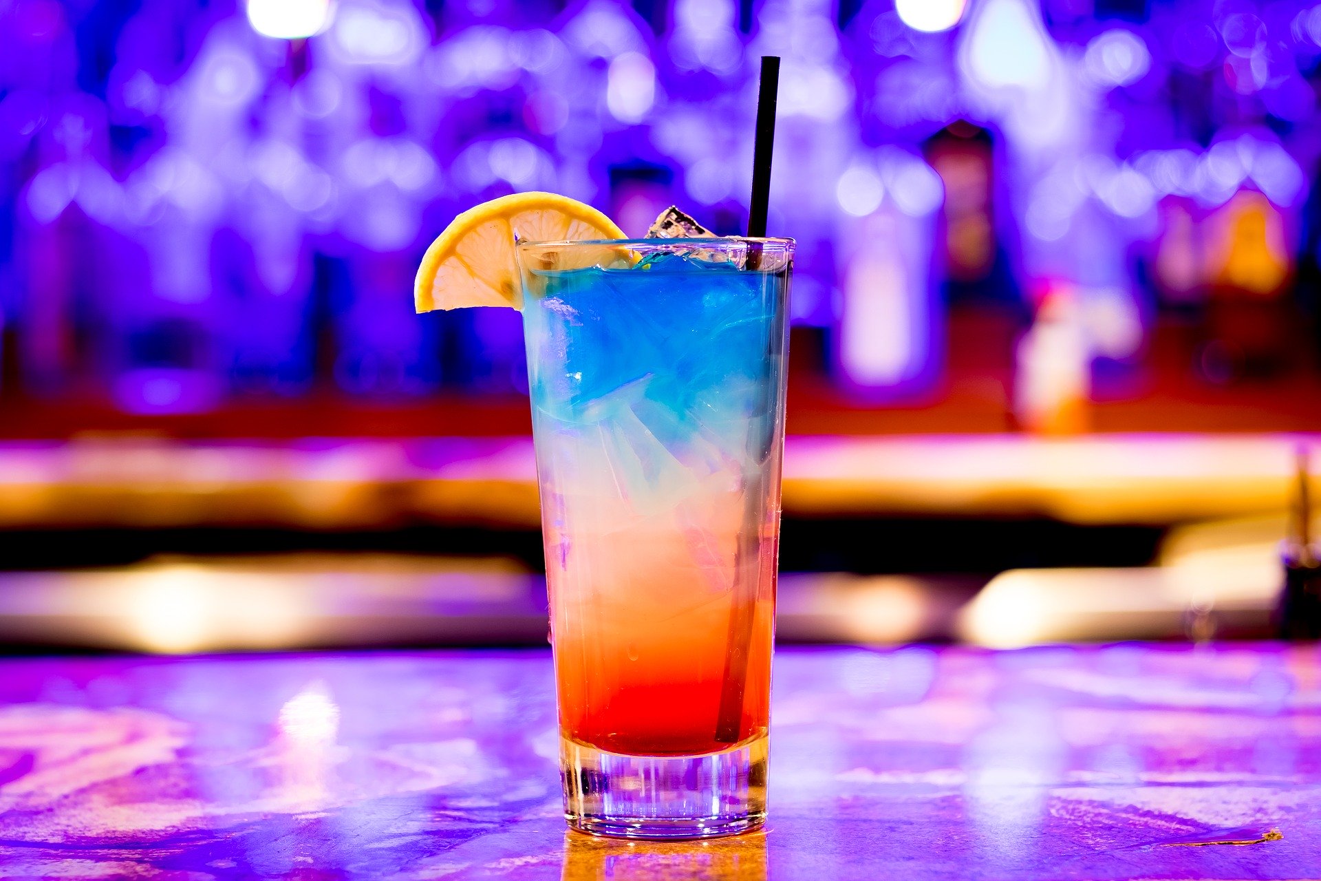 pahar de cocktail inalt, multicolor, cu albastru, alb si portocaliu, pe fundal albastru, unul din food trends pentru 2020