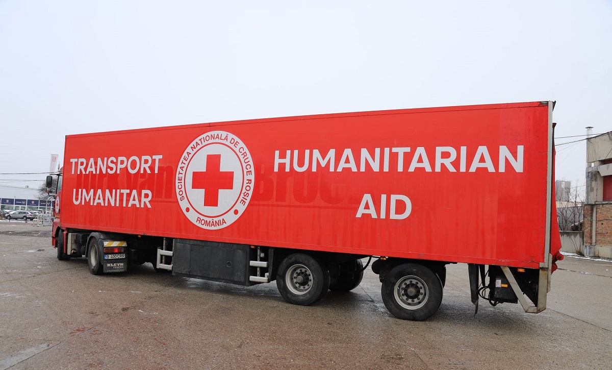 TIR roșu cu inscripțiile Crucii Roșii plin cu ajutoare din donații pentru refugiați
