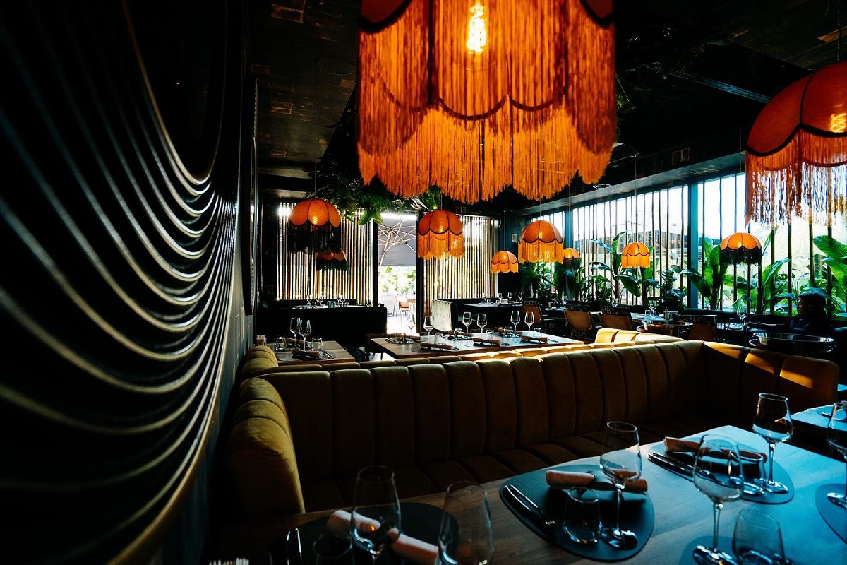 Elephant restaurant din București, iluminat difuz, cu lustre cu ciucuri, cu mese si canapele si pereti din sticlă, unul din restaurante noi București 2021