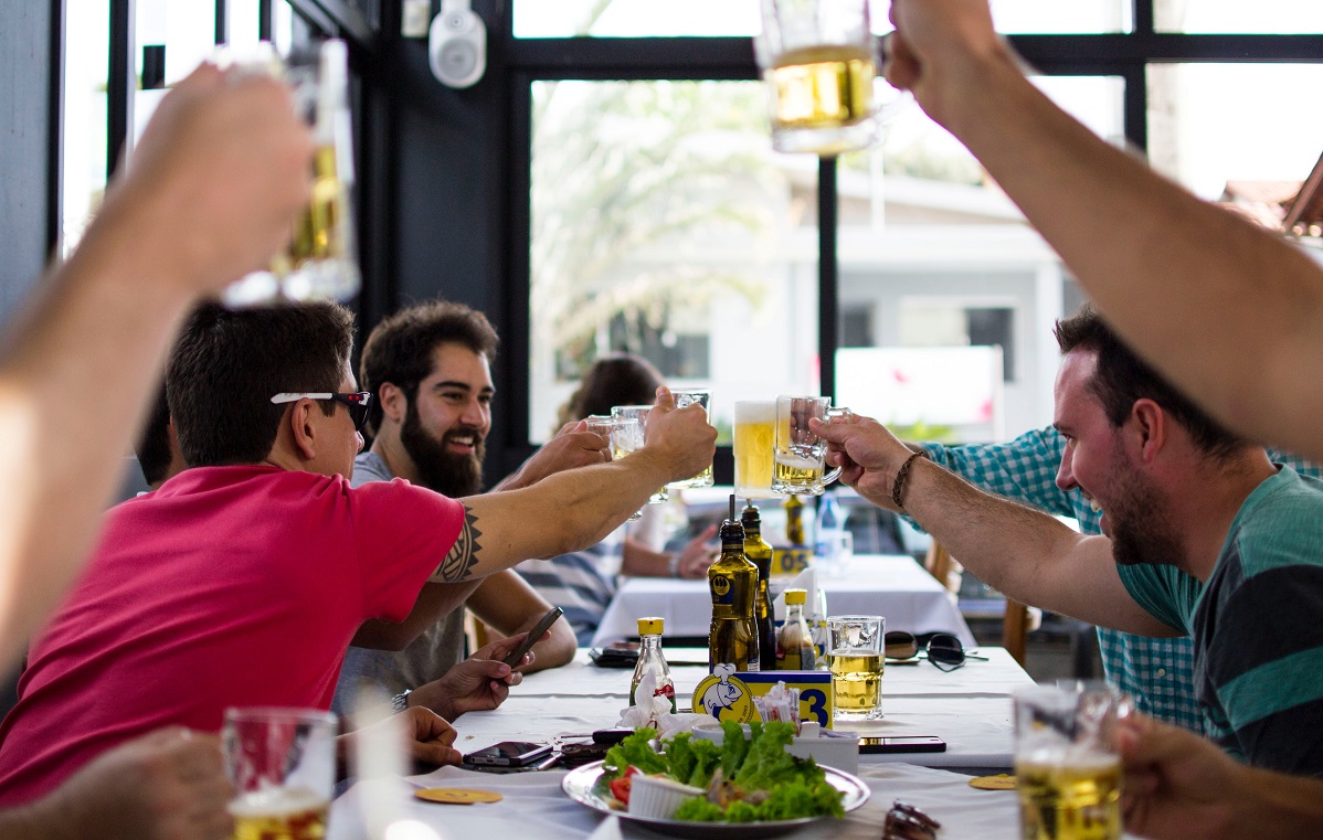 grup de barbati care ciocnesc halbe de bere la un restaurant ca imagine descriptiva pentru masuri de relaxare 15 mai