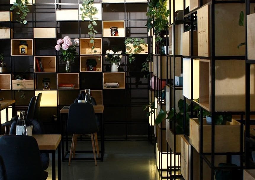 imagine din interiorul restaurantului Forager, cu pereti imbracati in rafturi cu cutii, borcane si elemente de decor, si mese, in culori inchise, unul din restaurante noi București 2021