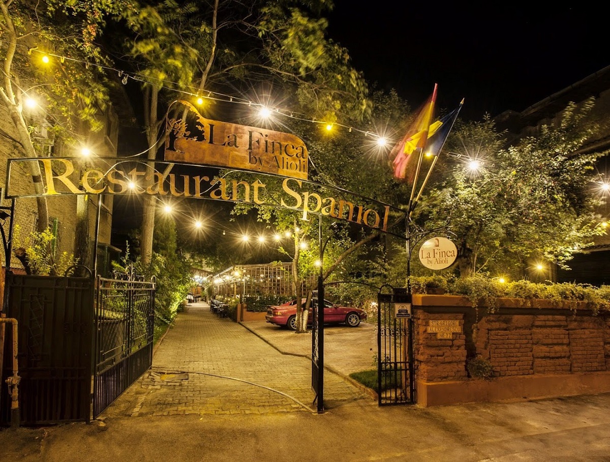 poarta de intrare in restaurant la finca by alioli, fotografiata noaptea, cu copaci in curte si beculete decorative