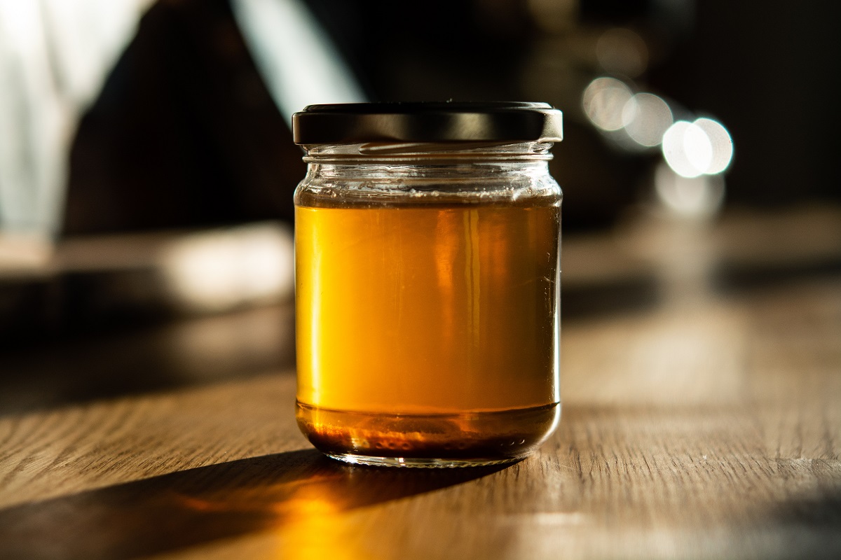 borcan de miere plin, cu capac metalic, fotoragiat pe blat in culoarea lemnului, unui din alimente afrodiziace