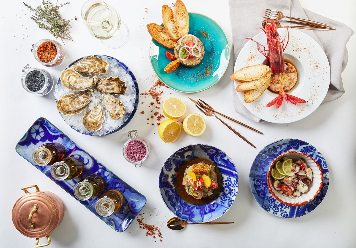 masa fotografiata de sus, cu multe farfurii cu preparate portugheze, in farfurii si boluri albe si albastre, la restaurant dancing lobster din barbu vacarescu
