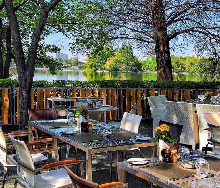 mese la terasa La Brasserie Bistro & Lounge din Herastrau, terasa langa lac, cu gard de lemn si copaci in jur