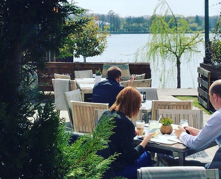 oameni luand masa la terasa de langa lac Herastrau Il Locale