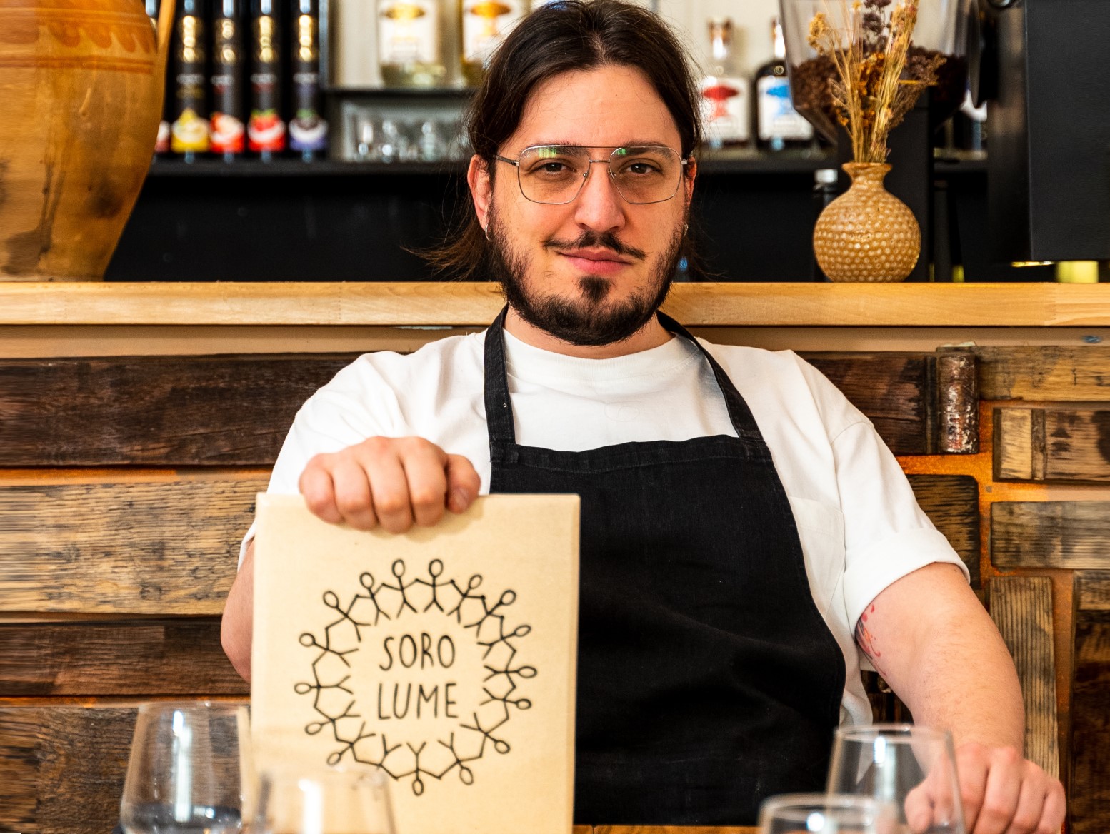 Chef Mihai Toader fotografiat la masa, cu meniul de la restaurant Soro.lume in mana