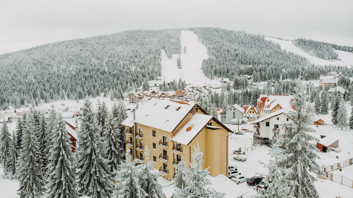 hotel Arieș fotografiat de sus, iarna, cu toate cladirile din jur ninse, iar in departare partia printre brazi - un loc und esă-ți faci Revelionul la munte in Apuseni